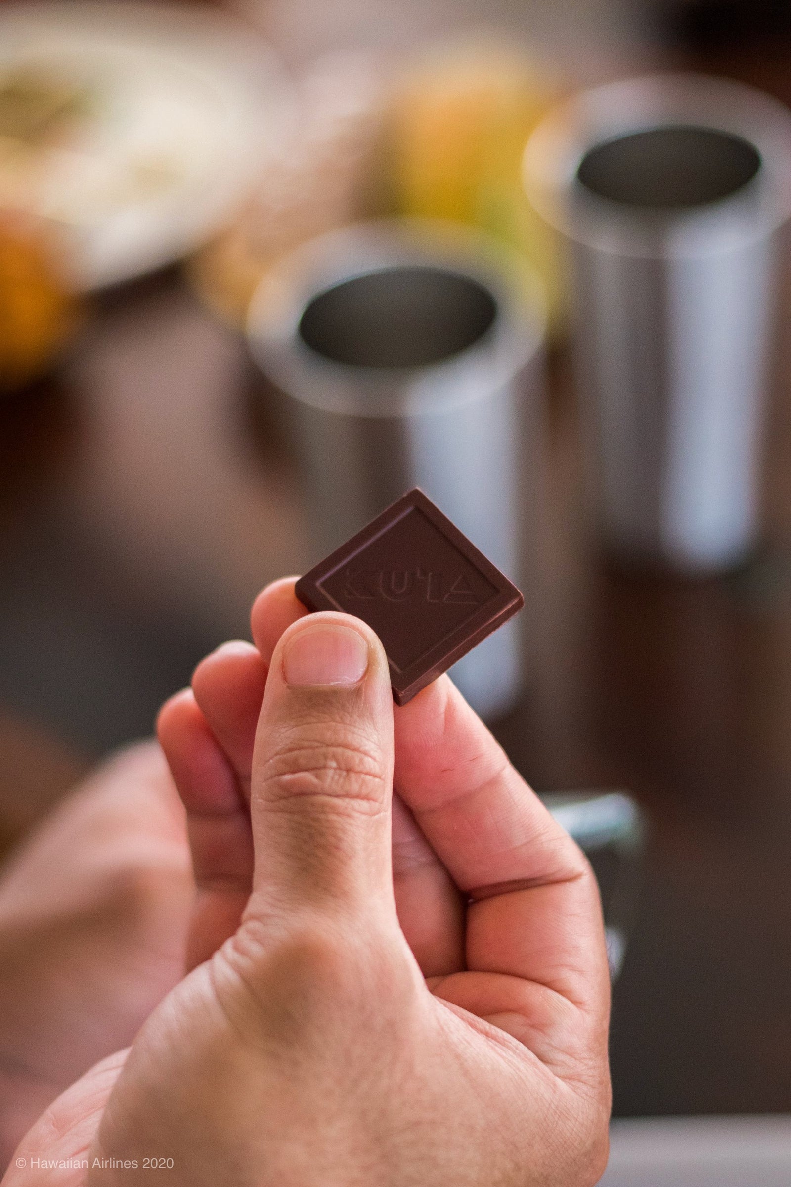 A person holding an unwrapped piece of Maui Ku'ia Estate Chocolate